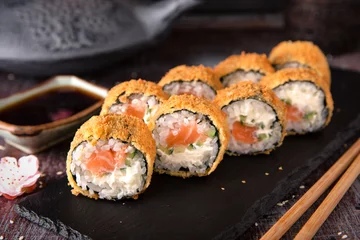 Foto auf Acrylglas Heiß gebratene Sushi-Rolle mit Lachs, Avocado und Käse. Sushi-Menü. Japanisches Essen. © Екатерина