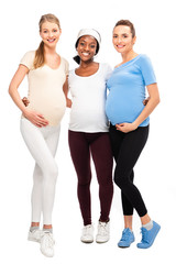 full length of three pregnant women standing and hugging isolated on white