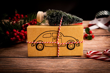 Prezent świąteczny. Świąteczny prezent z symbolem samochodu na drewnianym stole, kompozycja z miejscem na tekst. - obrazy, fototapety, plakaty
