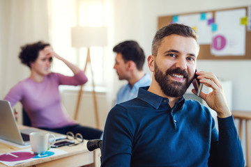 Young businessman in wheelchair with smartphone in a modern office.