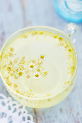 Fresh chamomile blossom tea in a glass cup on a wooden table, healthcare and healthy eating concept
