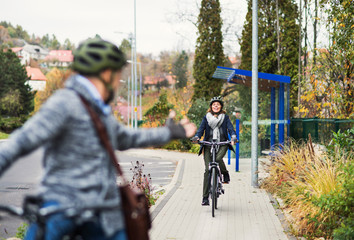 Obraz premium An active senior couple with electrobikes cycling outdoors on pathway in town.