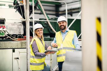 A portrait of an industrial man and woman engineer with tablet in a factory.