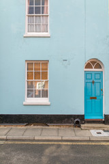 Fototapeta na wymiar Turquoise, blue and white typical english house facade with door and window viewed from outdoors.