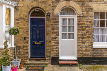Two doors from different houses in a brick wall, in the streets of an English village
