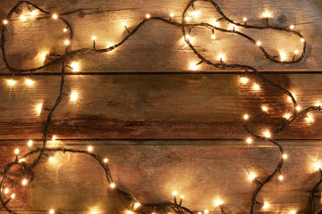 Overhead view of yellow Christmas lights spread over rustic wooden table, with copy space available...