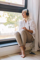 Woman listening to music on a window sill.