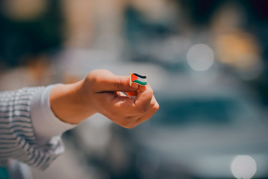 A person holding a flag button of Palestine. focused flag symbol background with space 