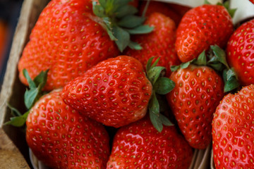 fresh, red, green strawberries are packed in baskets
