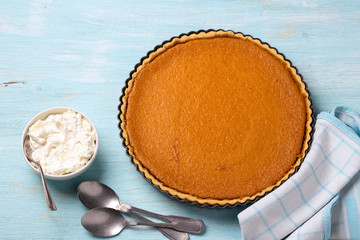 Homemade pumpkin pie with cream on a blue background, top view. tasty traditional food