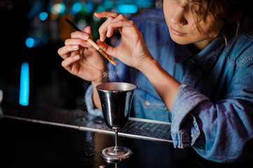 Woman adding a glitter from the brush to a cocktail glass with alcoholic drink