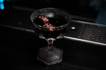 Cocktail glass with alcoholic drink decorated with rose petals