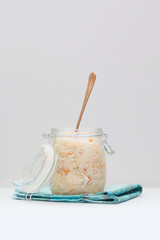 Homemade sauerkraut, marinated cabbage salad in a glass jar with a fork on a white table.  Fermented healthy vegetarian food concept. Copy space.