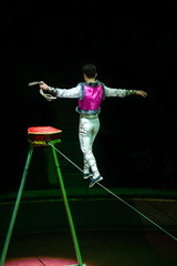 Acrobat walking on a rope during a performance in the circus 