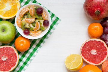 Bowl of healthy fresh fruit salad on white wooden background, top view, copy space