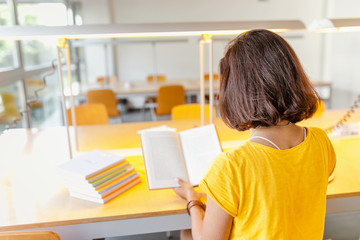 Asian mixed race woman reading book in library, education and lifestyle concept