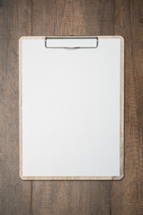 Mock up clip board and white paper on wood background.