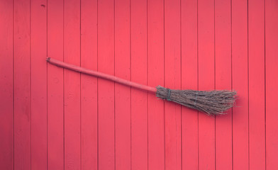 old broom on red wooden wall