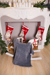 On a wooden horse by the fireplace there is a very thin gray blanket. Photo session in the studio.