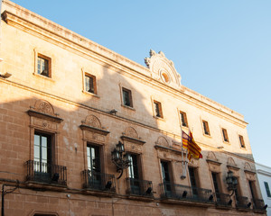 Baroque building with Spanish flags in the main square of the Ciutadella town of Menorca island