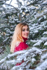 Outdoor waist up portrait. Young beautiful happy smiling girl walking on pine forest . Model with blue eyes,wearing stylish sweater. Magic snowfall. Space for text