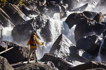 Happy man with backpack enjoying amazing waterfall Travel Lifestyle and success concept vacations into the wild nature