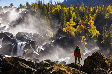 Photographer with backpack enjoying amazing waterfall Travel Lifestyle and success concept...