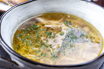 Bowl of chicken soup. Chicken soup in a white plate on a black wooden table. Free space for text. View from above. Top view.