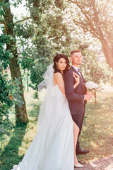 Beautiful wedding couple outdoor portrait. Young pretty bride hugging groom at nature.  Fine art lifestyle portrait of loving pair. Wedding photosession. Second half. Just married. Happy bridal day.