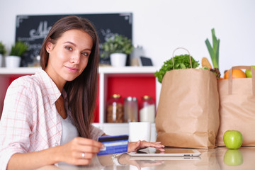 Young woman in the kitchen, using her ipad. Young woman