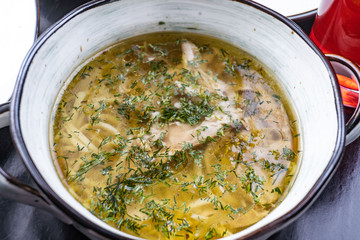 Bowl of chicken soup. Chicken soup in a white plate on a black wooden table. Free space for text. View from above. Top view.
