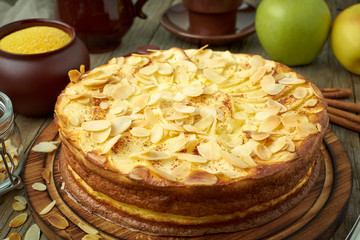 Cheesecake, apple pie, curd dessert with polenta, apples, almond flakes and cinnamon on dark wooden...