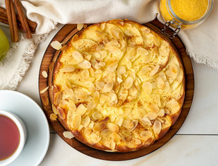 Cheesecake, apple pie, curd dessert with polenta, apples, almond flakes and cinnamon on white marble kitchen table, top view,
