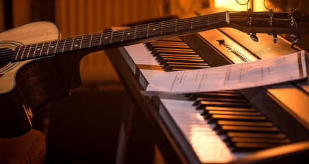 acoustic guitar stands on piano with notes, close-up, beautiful color background