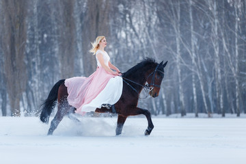 Young woman in dress riding horse on winter field © skumer