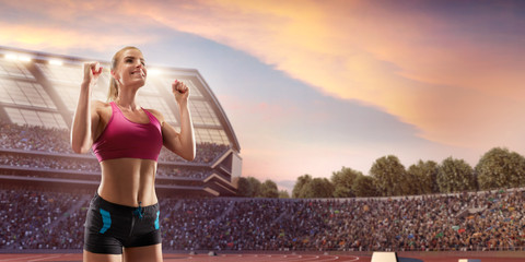 Happy female athlete. Woman sprinter in sport clothes emotionally rejoices victory at the running...