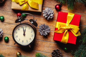 Christmas gift boxes and little alarm clock near pine branch on wooden table. Hight angle point of view