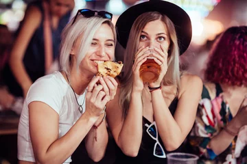 Fototapeten Female friends eating and drinking at music festival © Astarot