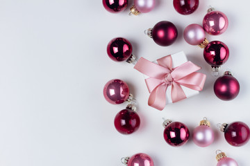 Christmas flat lay scene with pink aтd violet glass balls and gift box with copy space on white