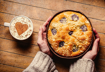 Homemade pie near cup of coffee on wooden table. Above view