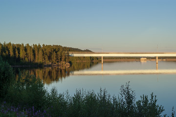 Obraz premium View of a railway bridge over a blue calm lake during sunset with a clear blue sky in northern Sweden.Photo taken July 2017.