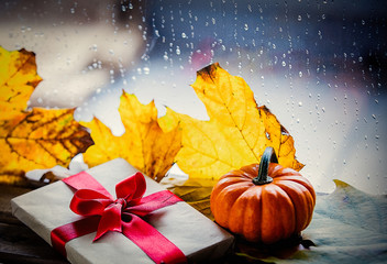 Naklejka na ściany i meble Gift box and maple leaves near window with rain drops.