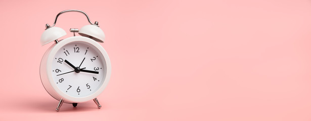 White alarm clock on pastel pink background. - obrazy, fototapety, plakaty