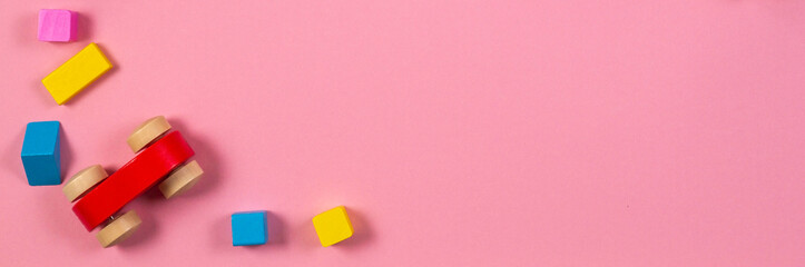 Wooden toy car with colorful cubes on pink banner background