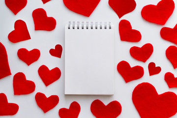 Notebook on the red felt hearts background. Valentine's Day concept. Top view, copy space, mock up