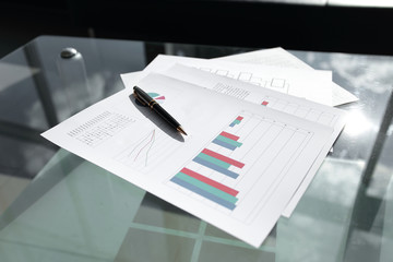 financial chart and pen on glass table in office