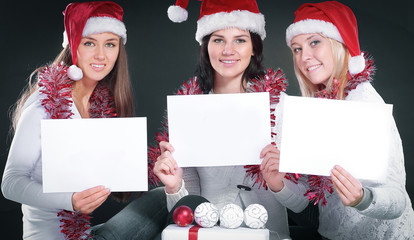 three happy young girls dressed as Santa Claus sitting with a bu