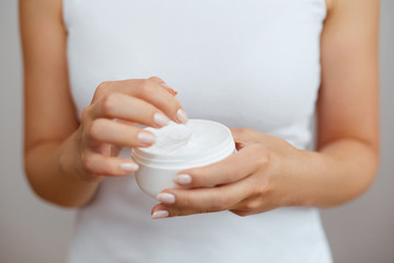 Obraz na płótnie Canvas Closeup shot of woman hands holding cream and applying moisturizing hand cream. Beautiful female hands with cream. Hand Skin Care. A woman uses body lotion on your arms. Beauty And Body Care Concept
