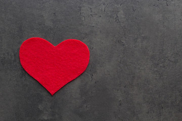 Heart carved from red felt on the grey concrete background. Love concept for Mother's day and St. Valentine's day. Top view, flat lay, copy space