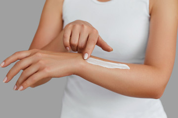 Closeup shot of woman hands holding cream and applying moisturizing hand cream. Beautiful female hands with cream. Hand Skin Care. A woman uses body lotion on your arms. Beauty And Body Care Concept